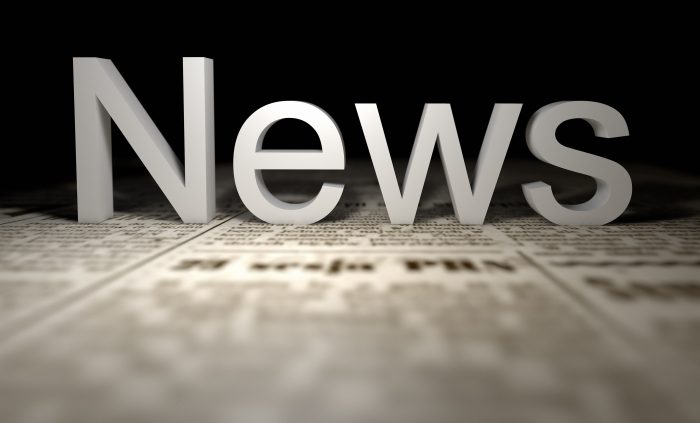 Large white 3D word 'News' rising from blurred newspaper pages against a dark background, like a banner headline.